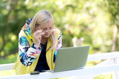 Heyecanlı iş kadını şehir parkında dizüstü bilgisayara bakıyor.