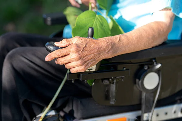 Elderly hand on a wheelchair.