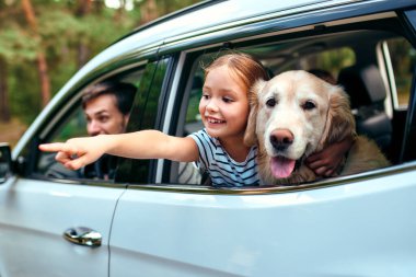 Arkadaşı köpek Labrador 'la küçük şirin bir kız çocuğu ve ailesi hafta sonunu neşeyle pencereden dışarı bakarak geçiriyorlar. Boş zaman, seyahat, turizm..