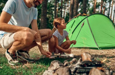 Genç bir baba ve kızı hafta sonu çam ormanında çadır başında kamp ateşinin yanında oturur ve mangal yapar. Kamp, dinlenme, yürüyüş..