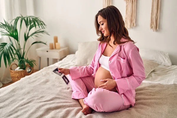 Mladá Těhotná Žena Jemně Drží Rukou Ultrazvukový Obrázek Svého Dítěte — Stock fotografie