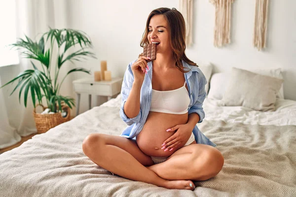 Mujer Embarazada Joven Sentada Cama Dormitorio Come Una Gran Barra —  Fotos de Stock