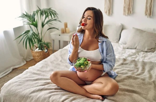 Mujer Embarazada Joven Sentada Cama Dormitorio Con Plato Ensalada Fresca —  Fotos de Stock