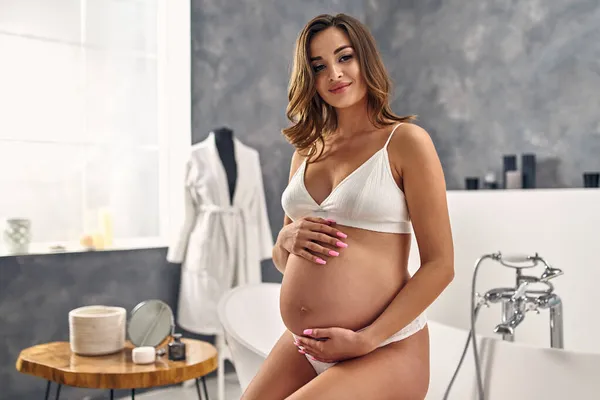 Uma Jovem Grávida Roupa Interior Branca Está Banheiro Segurando Mãos — Fotografia de Stock