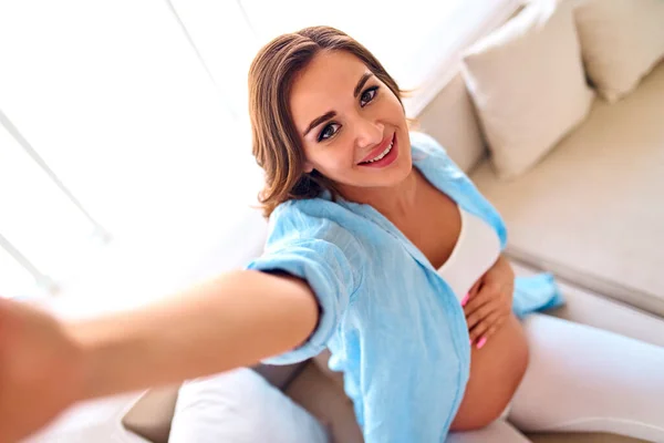 Mujer Embarazada Joven Sentada Sofá Hace Una Selfie Teléfono Inteligente —  Fotos de Stock