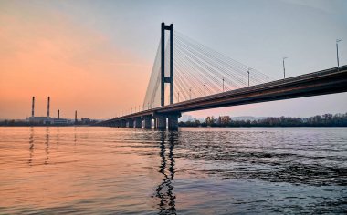 Gün batımında şehir nehri üzerinde tek pilonlu köprü..