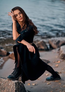 Gün batımında kumsalda poz veren uzun saçlı güzel bir esmerin portresi. Doğanın keyfi..