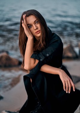 Gün batımında kumsalda poz veren uzun saçlı güzel bir esmerin yakın plan portresi. Doğanın keyfi..