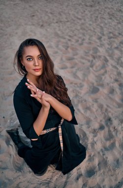 Gün batımında kumsalda poz veren uzun saçlı güzel bir esmerin portresi. Doğanın keyfi..