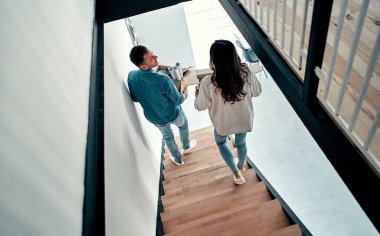 Yeni bir eve taşınıyorum. Merdivenlerden inerken ellerinde karton kutular olan mutlu genç çift..