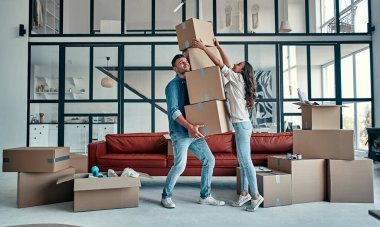 Taşınmak, ev almak, apartman konsepti. Düşen kutularla dolu genç bir çift onları yakalamaya çalışıyor..