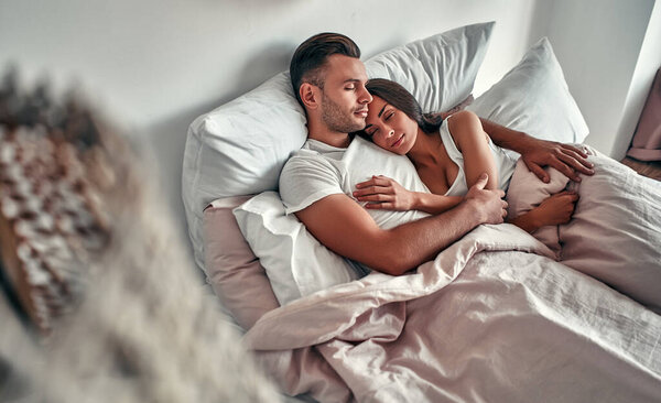 Young couple in love sleeps in bed in an embrace. The morning of a married couple.