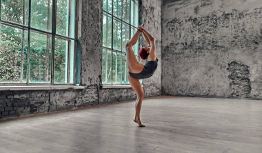 Gri mayolu genç atletik kadın jimnastik yapıyor. Yoga konsepti. Kız esneme hareketleri yapıyor..
