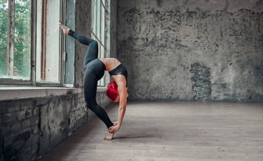 Siyah taytlı genç atletik kadın pencerenin yanında jimnastik yapıyor. Yoga konsepti. Kız esneme hareketleri yapıyor..