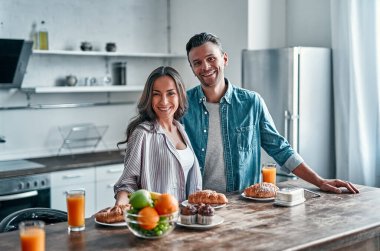 Mutfakta kahvaltıya hazırlanan romantik genç bir çift. Çekici genç bir kadın ve yakışıklı bir erkek aydınlık modern mutfakta dururken birlikte vakit geçirmekten zevk alıyorlar..