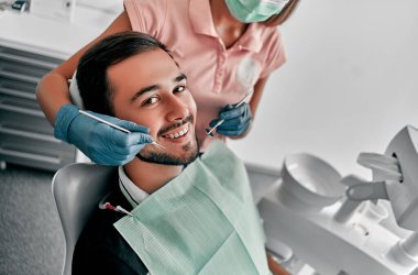 Kadın dişçi ile stomatoloji kliniğinde çekici bir genç adam. Sağlıklı diş konsepti.