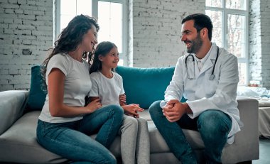 Amerikalı doktor, genç çocuk ve anneyle konuşuyor..