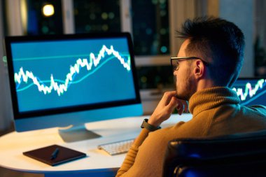 Bilgisayar ekranına bakan kripto tüccar yatırımcısı analizcisi bilgisayar ekranındaki finansal verileri analiz ediyor ve bilgisayar ekranında online borsa ticareti, yatırım ticareti gibi küresel riskleri düşünüyor..