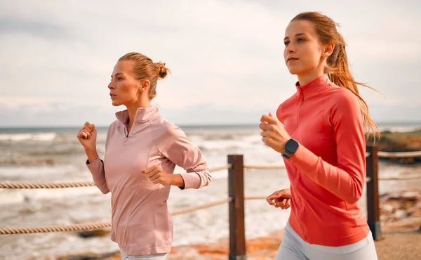 Spor giyimli, narin genç kadınlar deniz kenarında geziniyorlar. Sabah koşusu. Spor ve Eğlence..