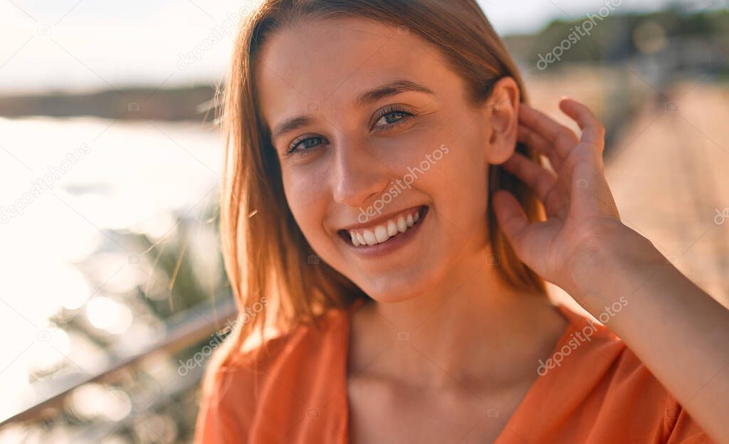 Young stylish woman business lady or student stands on the coast in sunny weather. Close-up image