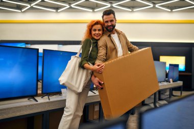 Mutlu genç çift, ev aletleri, elektronik eşyalar ve aletlerle dolu yeni bir televizyon satın aldı. Yeni bir televizyon, indirim günü..