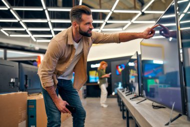 Adam düşünceli ve dikkatli bir şekilde plazma TV 'yi ev aletleri, elektronik aletler ve aletler deposundan seçiyor. Yeni bir televizyon, indirim günü..