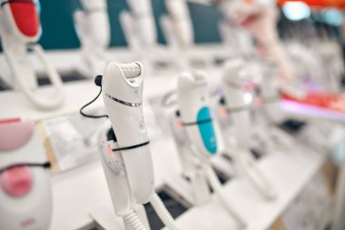 Bir alet, elektronik eşya ve ev aletleri mağazasında rafta duran kadınlar için epilatörler var. Vücut bakımı araçları.