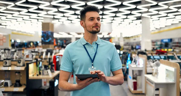 Jovem Assistente Vendas Bem Sucedido Uniforme Com Tablet Suas Mãos — Fotografia de Stock