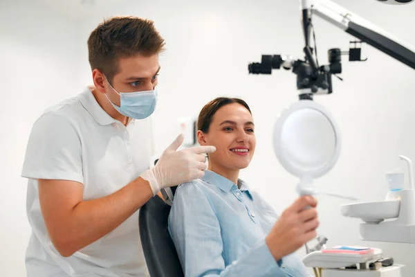 Lachende Vrouwelijke Patiënt Met Beugels Kijken Spiegel Onderzoek Bij Tandarts — Stockfoto