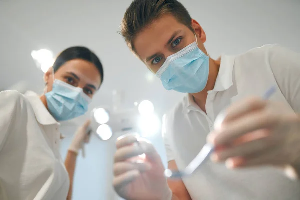 Primer Plano Las Caras Joven Dentista Asistente Máscaras Médicas Examinando —  Fotos de Stock