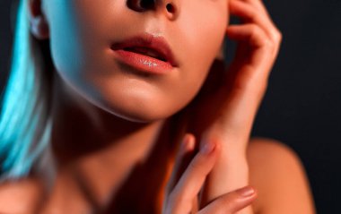 Çekici genç kız yüzüne dokunuyor. Gri bir arka planda mükemmel cilde sahip sarışın bir kızın fotoğrafı. Güzellik ve cilt bakımı kavramı.