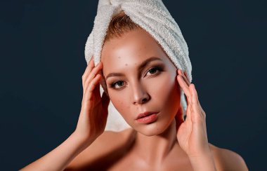 Kafasında havluyla sivilceleri yüzünden şokta olan kaşlarını çatan bir kız. Kadın cilt bakımı konsepti / Gri arka planda çirkin sorunlu cilt kızının fotoğrafları