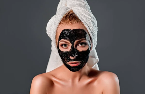 顔に黒い剥がしマスクをした美少女 灰色の背景で温泉治療を受けている幸せな女の子の写真 スキンケアのコンセプト — ストック写真
