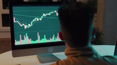 Bilgisayar ekranına bakan kripto tüccar yatırımcısı analizcisi bilgisayar ekranındaki finansal verileri analiz ediyor ve bilgisayar ekranında online borsa ticareti, yatırım ticareti gibi küresel riskleri düşünüyor..