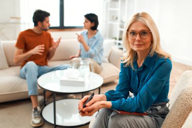 Mutsuz çift tartışıyor, tartışıyor, psikolog ofisinde anlaşmazlık yaşıyor, genç ailenin terapistleriyle ilişki sorunlarını tartışıyor..