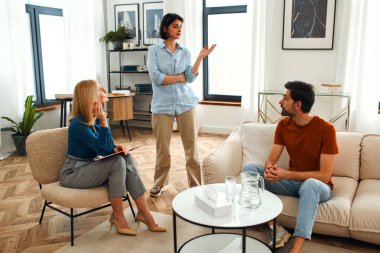 Mutsuz çift tartışıyor, tartışıyor, psikolog ofisinde anlaşmazlık yaşıyor, genç ailenin terapistleriyle ilişki sorunlarını tartışıyor..