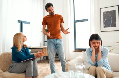 Mutsuz çift tartışıyor, tartışıyor, psikolog ofisinde anlaşmazlık yaşıyor, genç ailenin terapistleriyle ilişki sorunlarını tartışıyor..