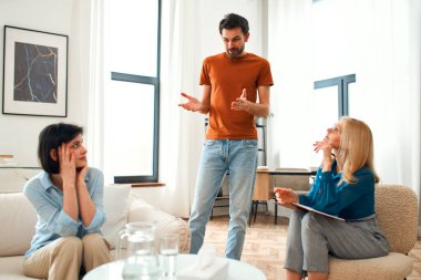 Mutsuz çift tartışıyor, tartışıyor, psikolog ofisinde anlaşmazlık yaşıyor, genç ailenin terapistleriyle ilişki sorunlarını tartışıyor..