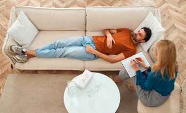 Ruh sağlığı seansı sırasında kadın psikoloğun resepsiyonunda kanepede yatan depresyondaki genç bir adam. Bir psikologa karşı hayal kırıklığına uğramış, stresli bir adam..