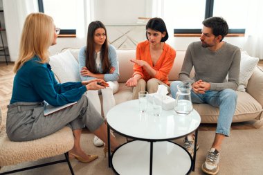 Psikolog randevusunda ailesiyle birlikte üzgün bir genç kız. Aile psikoloji seansında. Genç çocukların sorunlarını çözmek için genç bir aileye yardım eden psikolog..