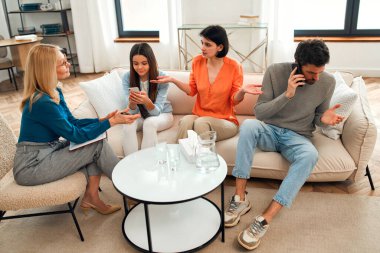 Ebeveynlerin psikolojik sorunları. Psikolog sosyal hizmet görevlisi annesiyle konuşurken ergen kız ve babası telefonla konuşuyor. Ebeveynlerin psikolojik sorunları, aile terapileri. Sosyal ağlarda sorun.