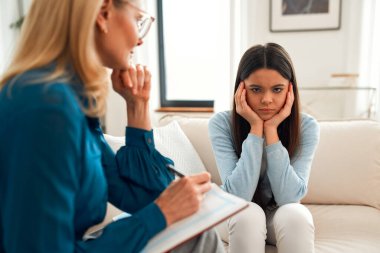 Bir psikoloğun resepsiyonundaki mutsuz kız. Müşteri sorunlardan bahsediyor. Aile sorunları, ergenlik sorunları. Bir terapistle konuşmak, tavsiye, yardım kavramı.