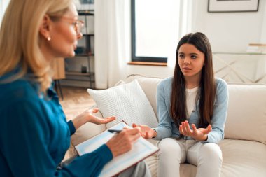 Bir psikoloğun resepsiyonundaki mutsuz kız. Müşteri sorunlardan bahsediyor. Aile sorunları, ergenlik sorunları. Bir terapistle konuşmak, tavsiye, yardım kavramı.
