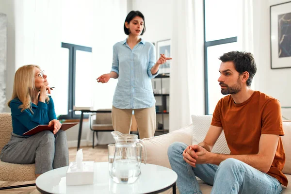 Mutsuz çift tartışıyor, tartışıyor, psikolog ofisinde anlaşmazlık yaşıyor, genç ailenin terapistleriyle ilişki sorunlarını tartışıyor..