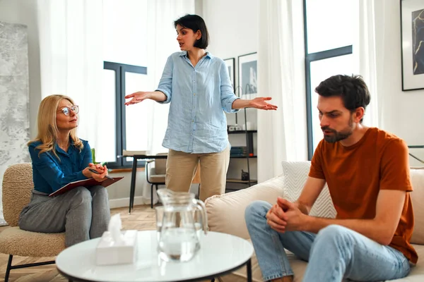 Mutsuz çift tartışıyor, tartışıyor, psikolog ofisinde anlaşmazlık yaşıyor, genç ailenin terapistleriyle ilişki sorunlarını tartışıyor..