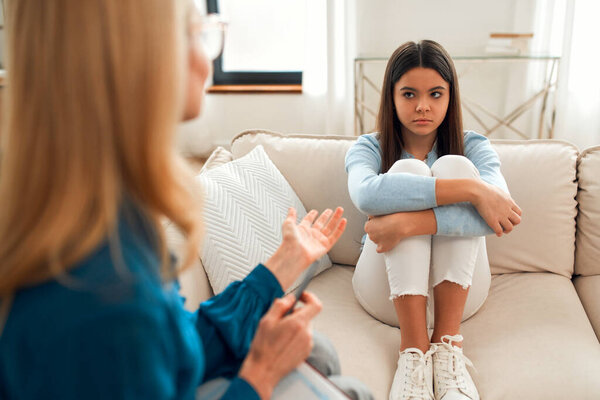 Unhappy girl at the reception of a psychologist. The client talks about problems. Family problems, teenage troubles. Talking with a therapist, advice, help concept.