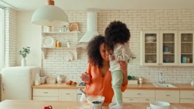 Kıvırcık saçlı ve mutfakta kurabiye yapan küçük kızı olan Afro-Amerikalı bir kadın. Anne ve kızı birbirlerini un ile kirletip oynuyorlar..