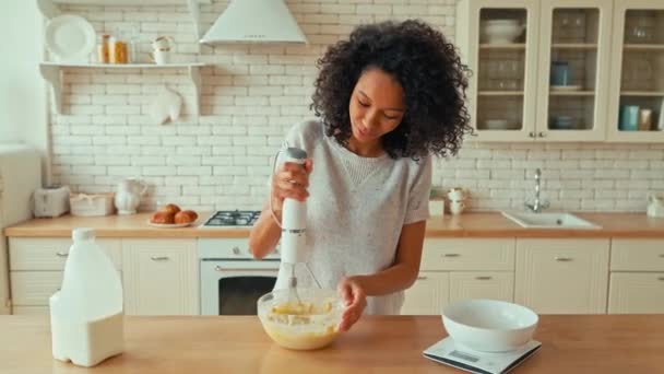 곱슬곱슬 귀여운 아프리카계 부엌에 쿠키를 반죽을 준비하면서 접시에 믹서를 계란을 — 비디오