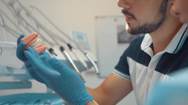 Male Dentist Shows Patient Artificial Model Jaw Braces How Properly — Wideo stockowe