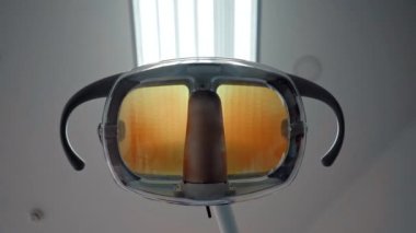 The dentist's hand turns on the dental lamp to examine the patient's mouth. Dental health.